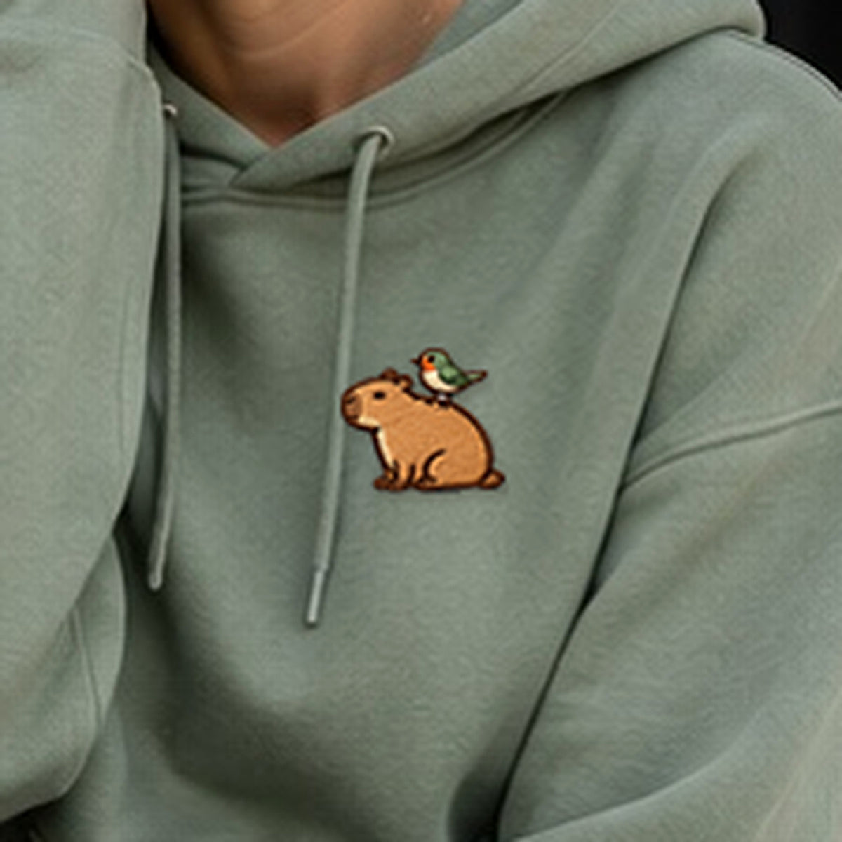 Detailansicht der Stickerei: Mellowbara_mit_Vogel – Kapuzenpullover mit kleiner Stickerei, nachgeschärft