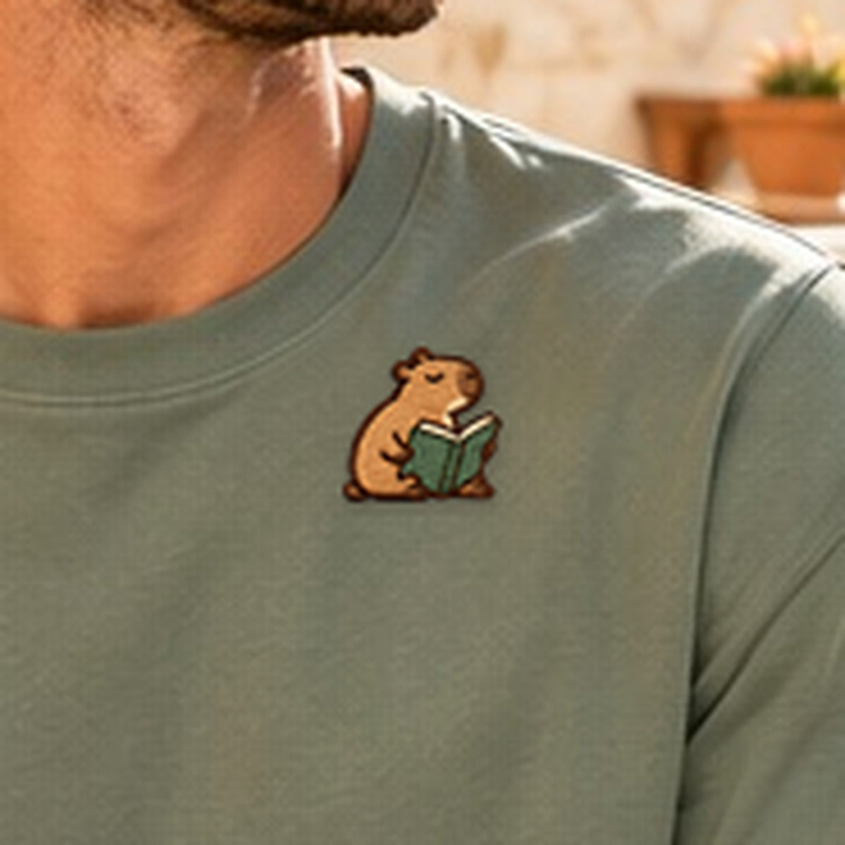 Detailansicht der Stickerei: Lesendes_Mellowbara – Herren-T-Shirt mit kleiner Stickerei, nachgeschärft